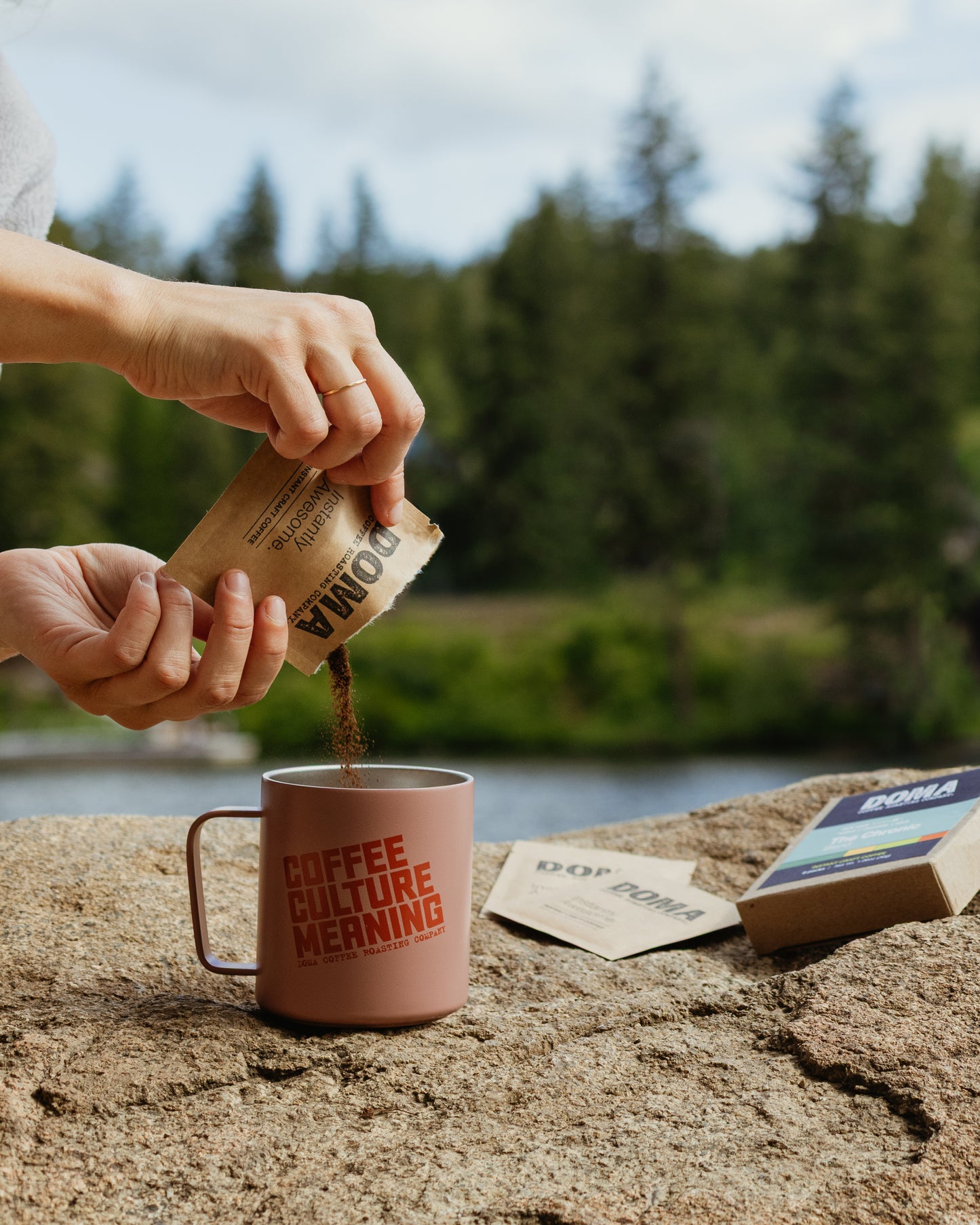Person pouring coffee into a pink mug with a scenic background