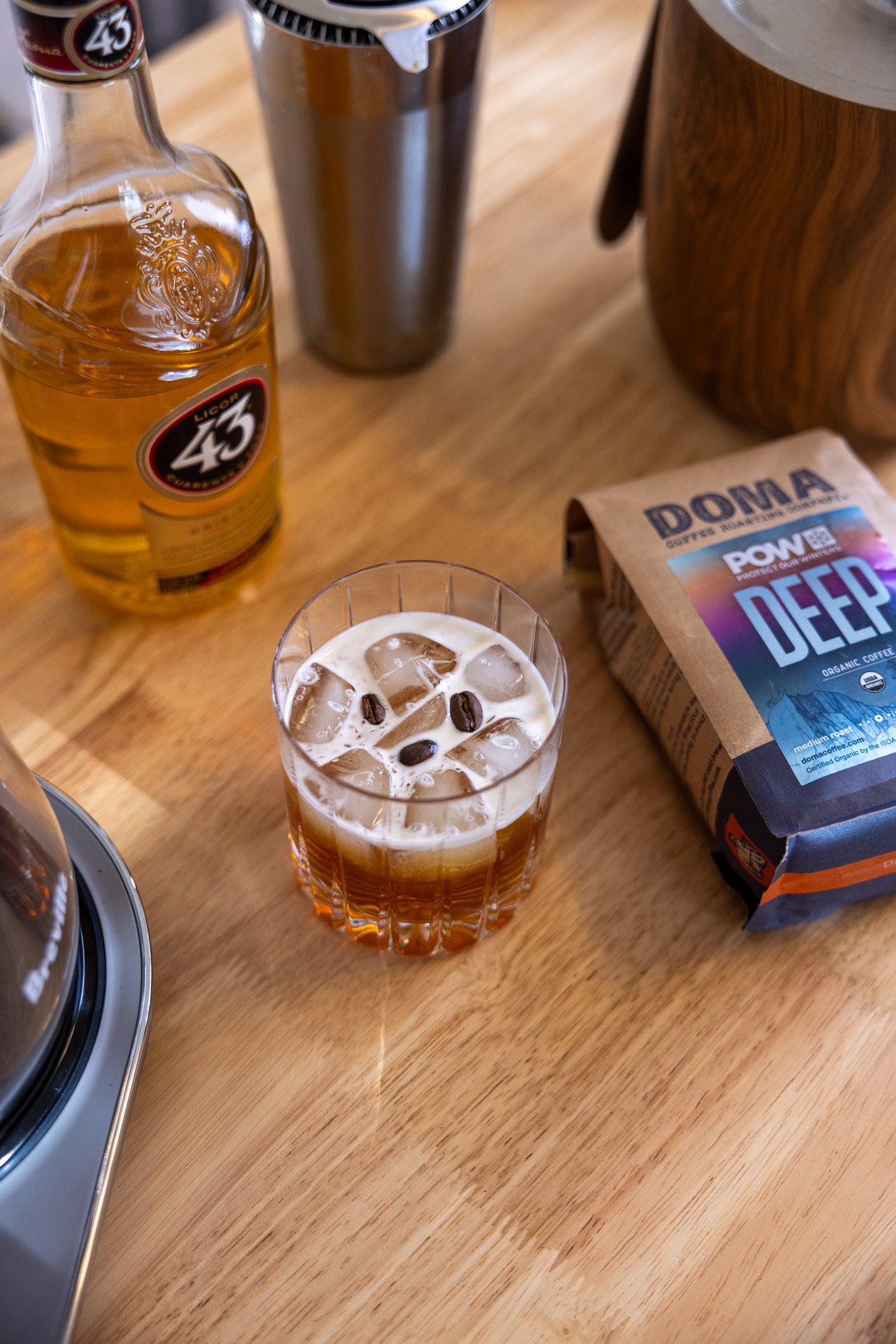Iced drink with bottle and package of DOMA coffee on a wooden surface
