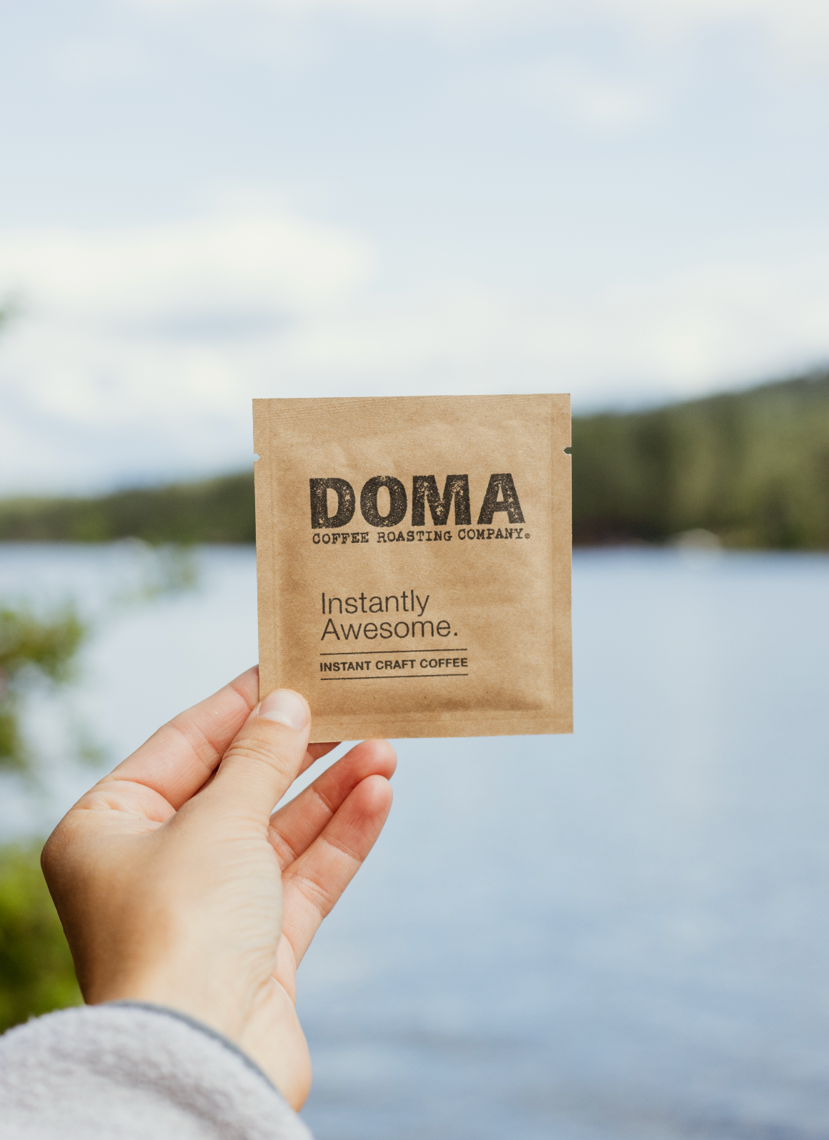 Hand holding a DOMA instant coffee package 