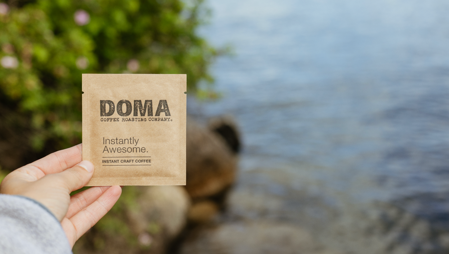 Hand holding a DOMA instant coffee package 